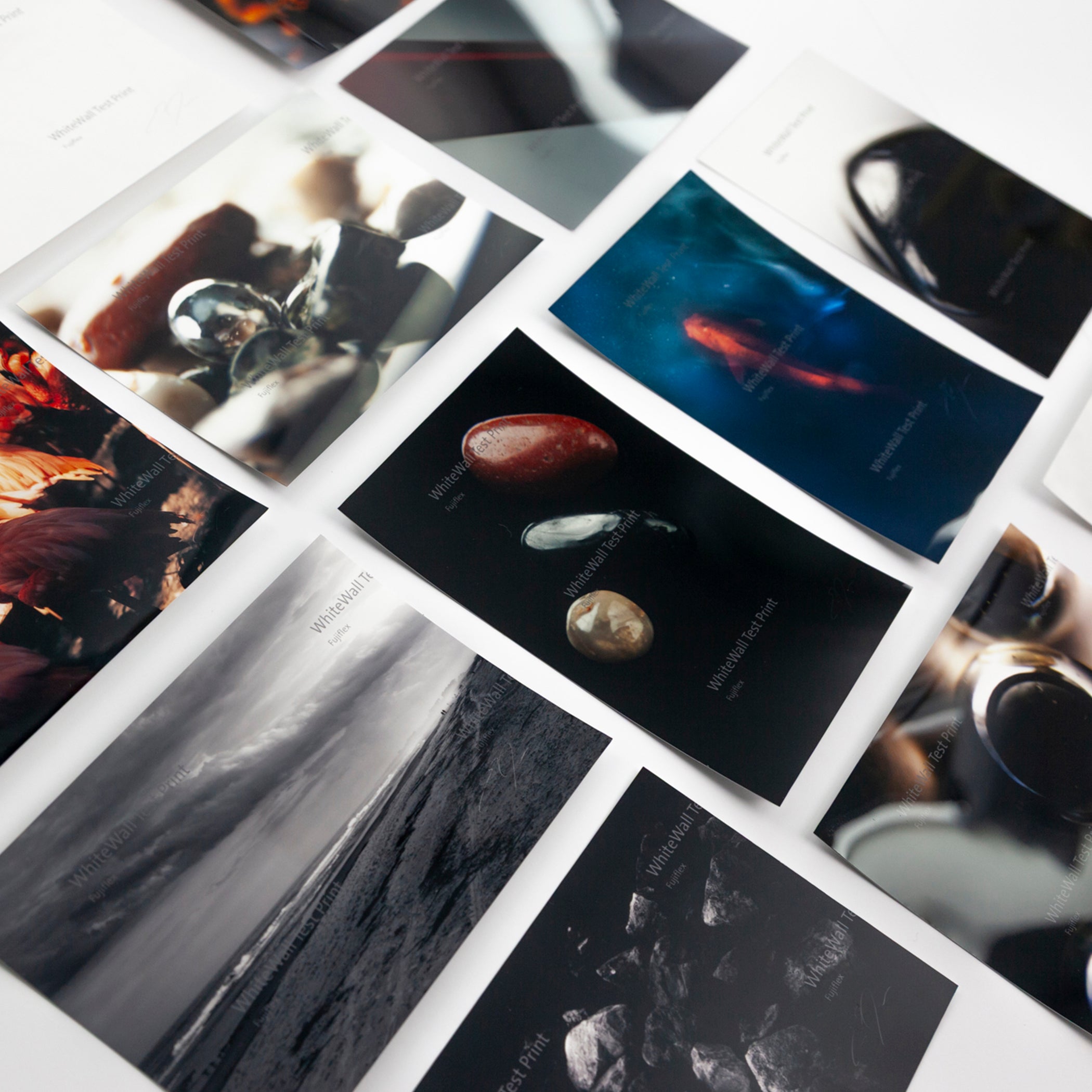 A collage of printed art cards or photo prints arranged on a white surface, showing abstract and nature-inspired imagery including stones, a red fish in blue water, a mountain landscape, and dark textured scenes.